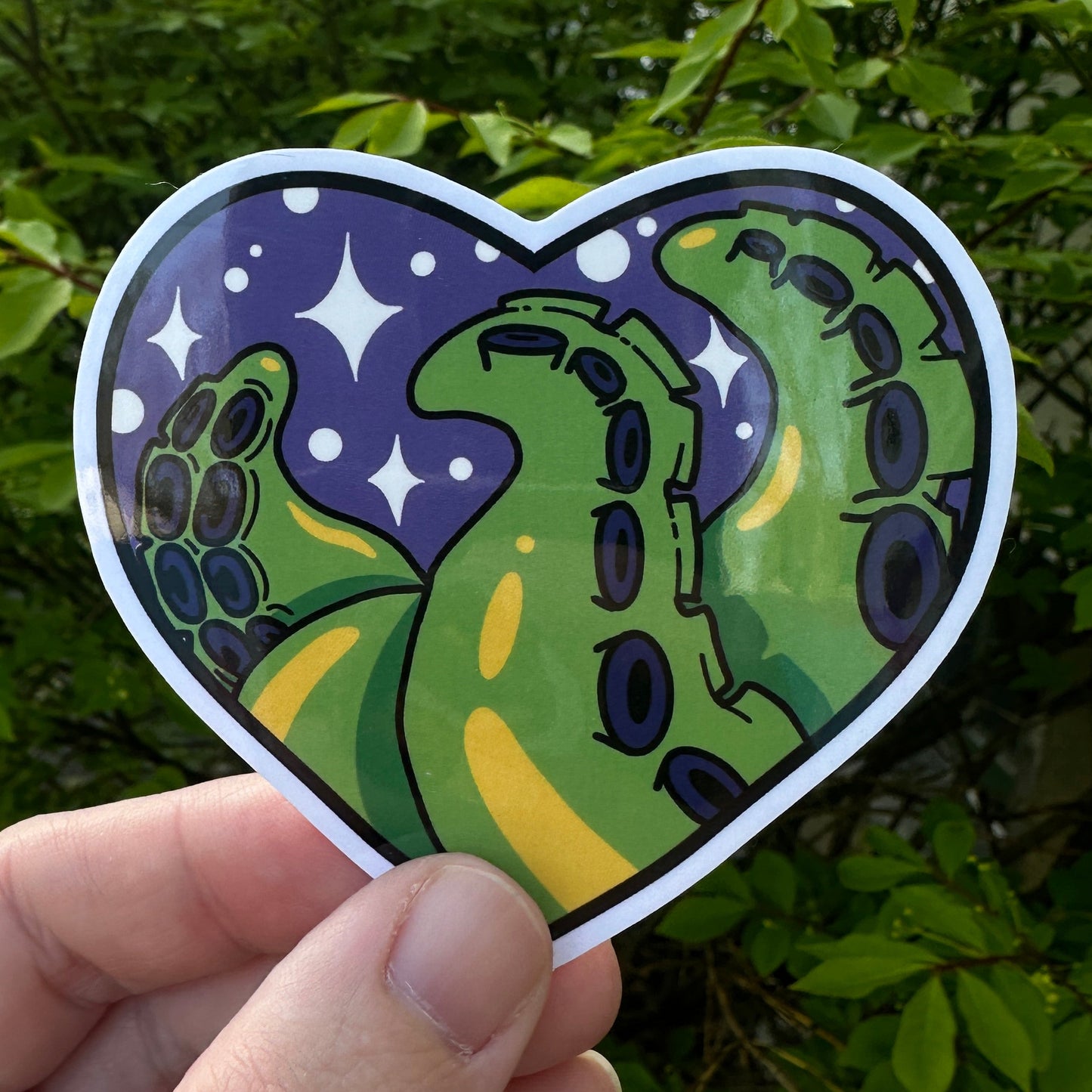 Heart shaped sticker with green tentacles on a purple background