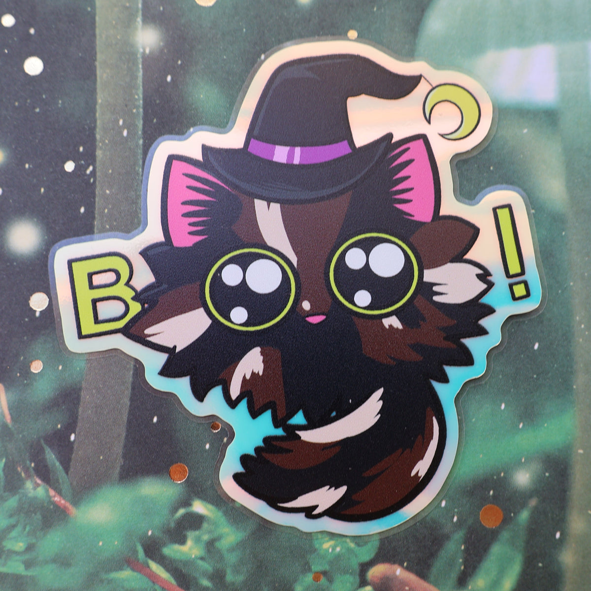 Tortoiseshell cat sticker with witch hat and eyes used to spell Boo. Holographic sheen.