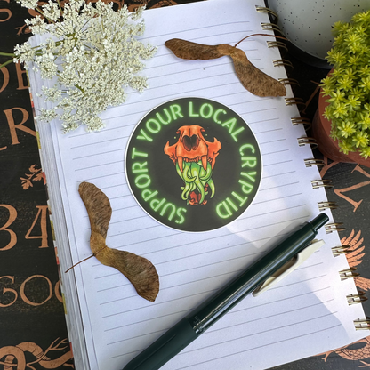 A sticker featuring a stylized illustration of an animal skull with vibrant green tentacles, and the text 'support your local Cryptid' around it.