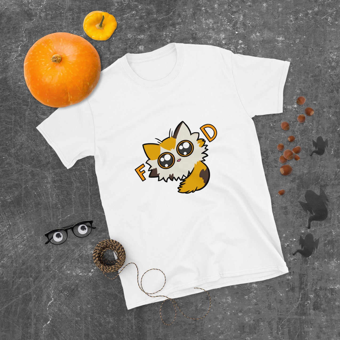 White t-shirt with a cartoon cat design on a gray surface with pumpkins and cat ears.