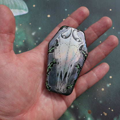 Hand holding horse skull coffin pin for scale