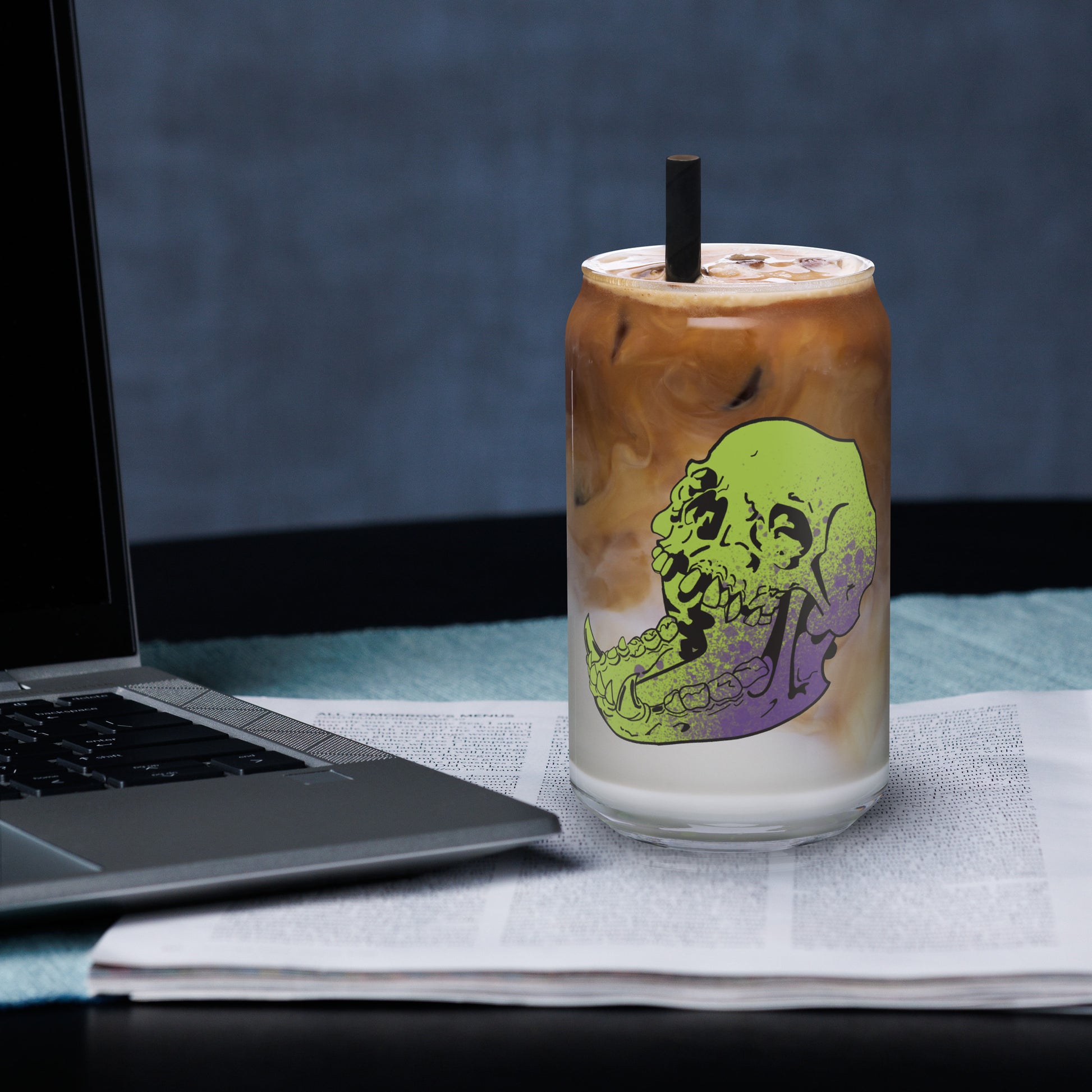 Can shaped glass featuring a human skull with an elongated lower jaw of an animal. Green with purple splatters