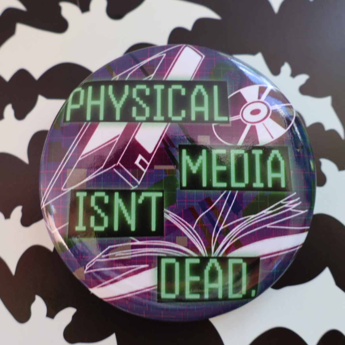 Pin with physical media isn't dead in retro computer font, background is vhs, cd, book tumbling in space.