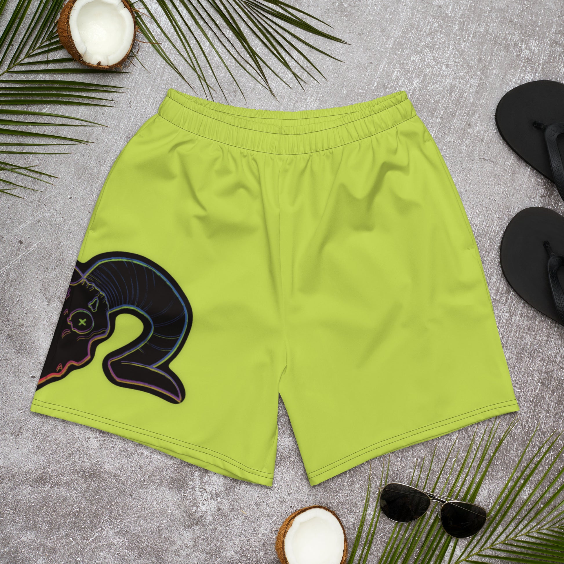 A pair of neon green unisex athletic long shorts with a graphic of a ram skull on the right leg, displayed on a coconut tree background with palm leaves and sunglasses.