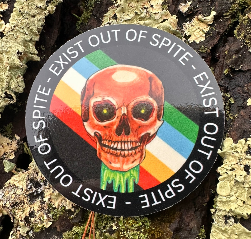 Round sticker with a skull over a disabled pride flag encircled by the text exist out of spite