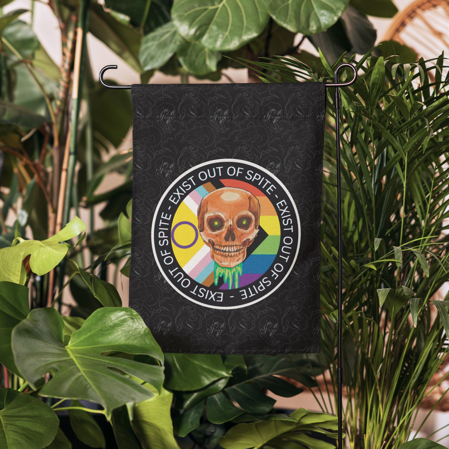 Garden flag with skull and rainbow design in front of green plants