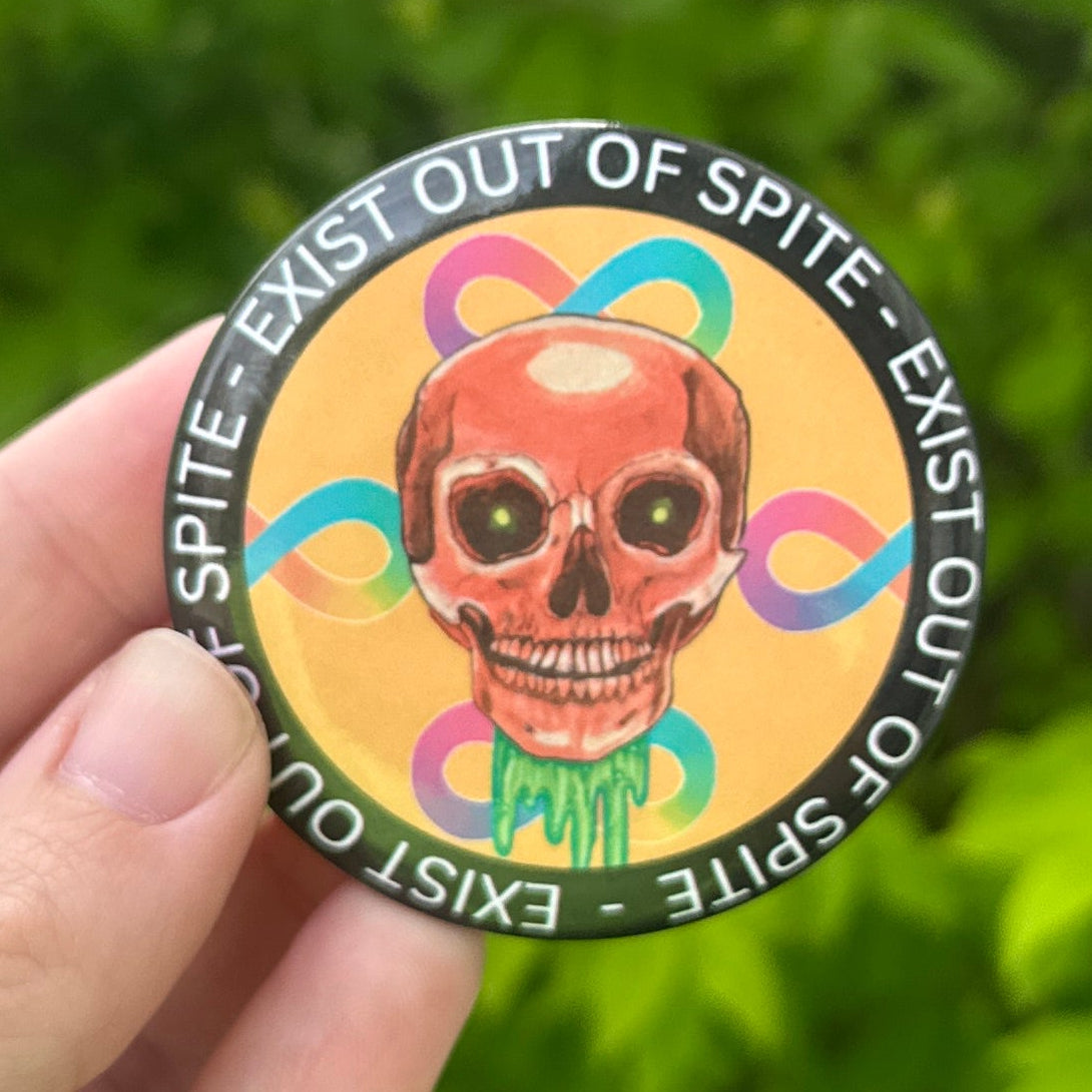 Hand holding a colorful button with text and graphics against a green leafy background