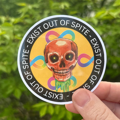 Hand holding a round sticker with a colorful design and text against a green leafy background