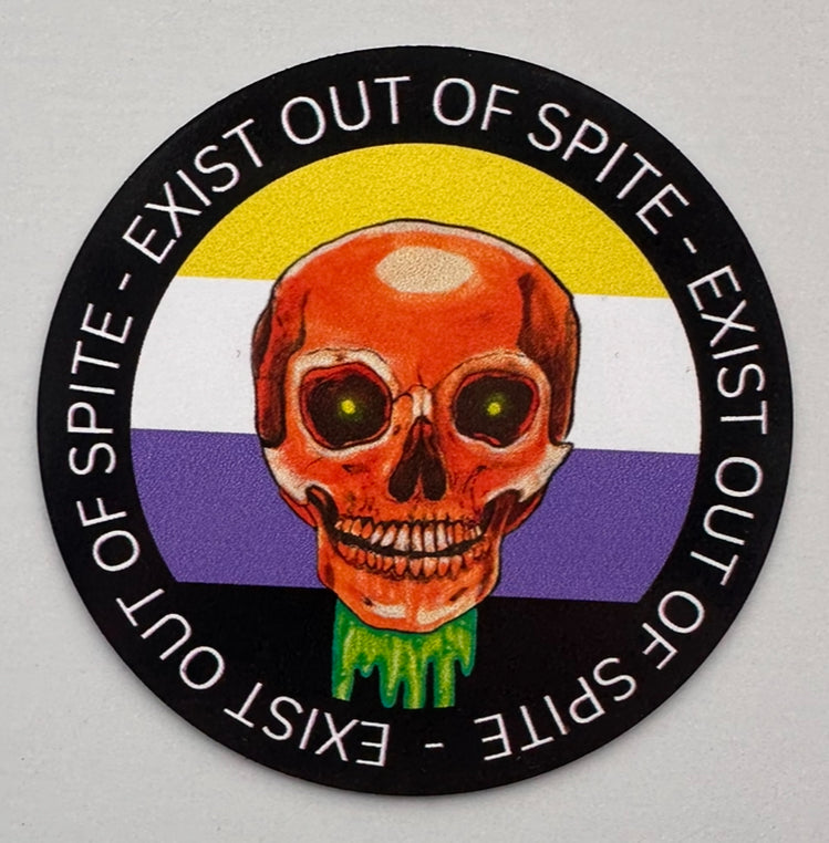 Round magnet with a skull over a nonbinary pride flag encircled by the text exist out of spite