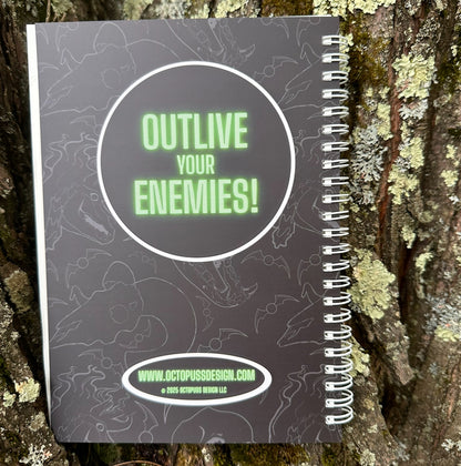 Back of journal with 'Outlive Your Enemies!' text on a textured surface