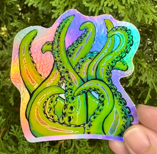Holographic sticker with green octopus design held in front of green foliage
